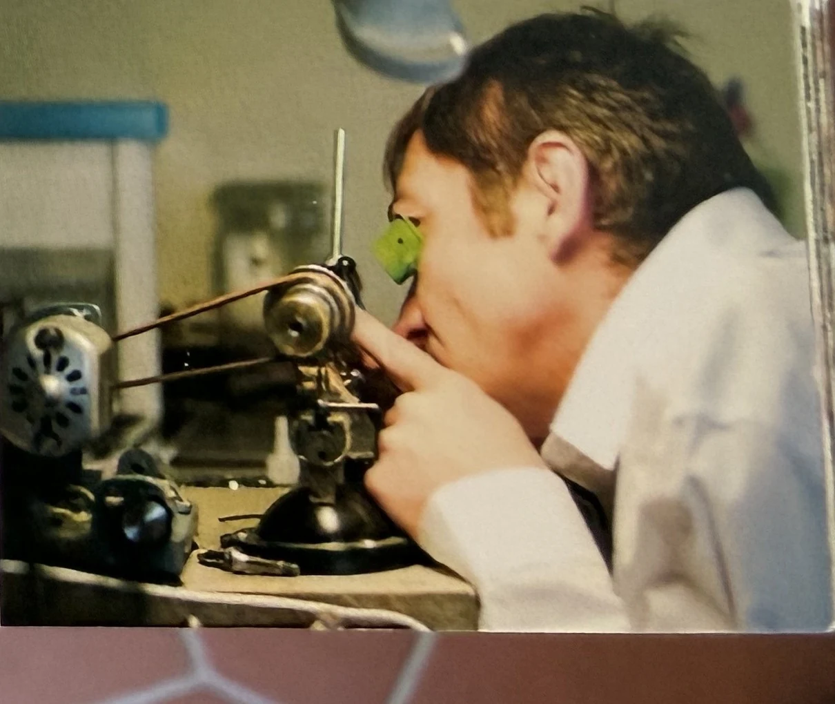 Uhrmacher prüft ein Werk durch die Uhrmacherlupe am Werktisch