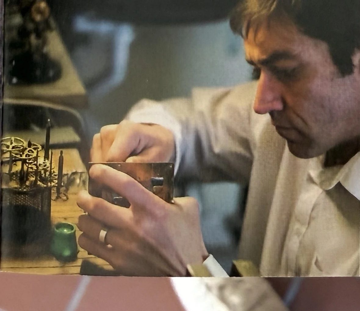 Uhrmacher bei der Feinarbeit an einem geöffneten Uhrwerk an der Werkbank des Ateliers