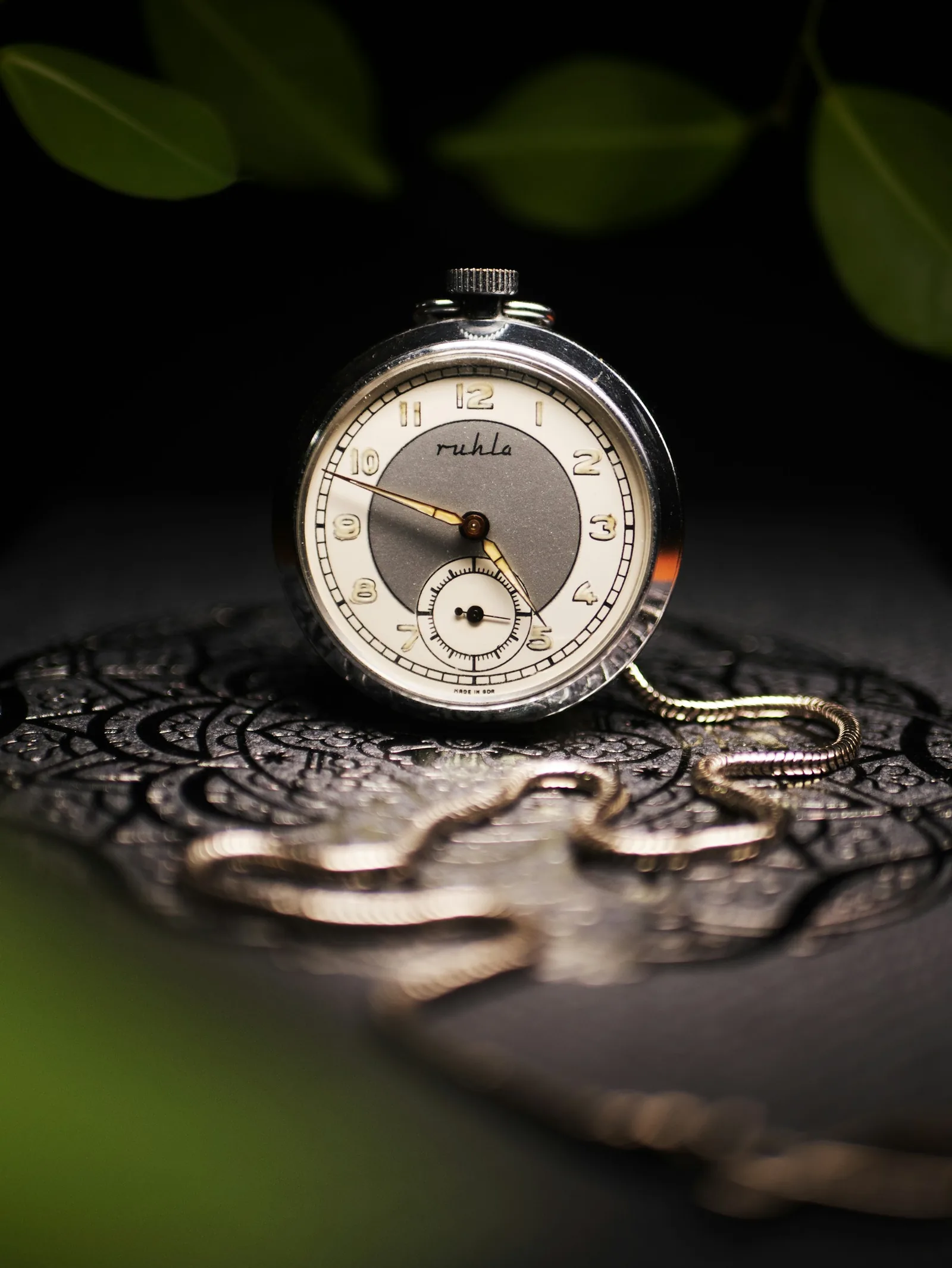 Symbolbild: historische Taschenuhr mit Kette auf einem verzierten dunklen Untergrund